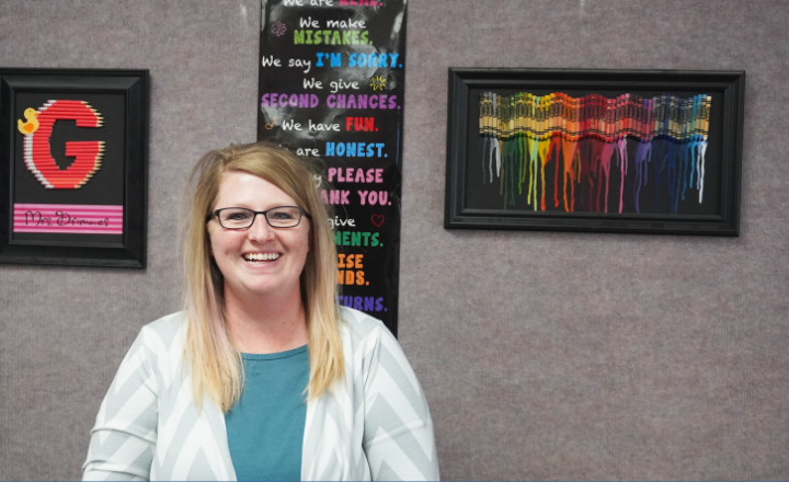  Ashley Grimnes smiles in front of her classroom wall display